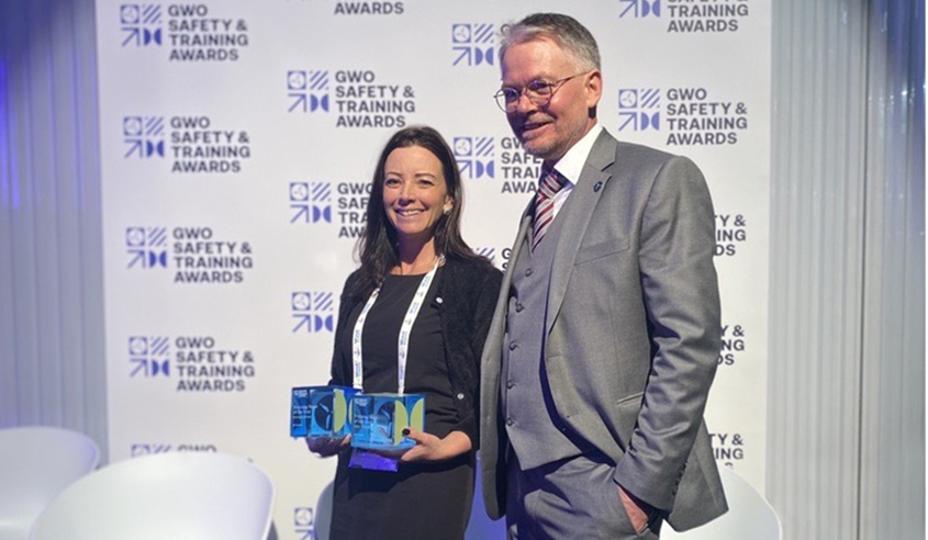 Two people stand in front of a backdrop with 