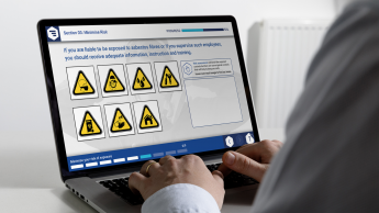 A person using a laptop showing a safety training module with various warning symbols displayed on the screen.