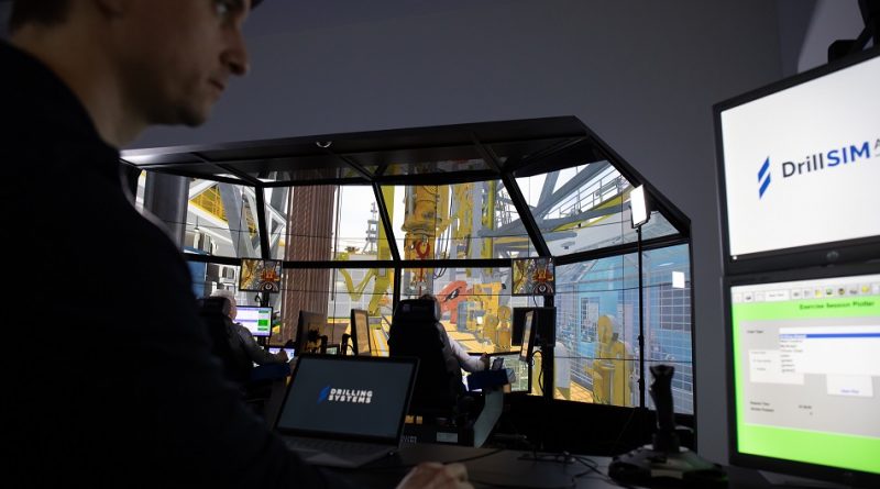 A person monitors multiple computer screens displaying drilling simulation software in a control room setting. The background shows a simulated drilling rig environment.