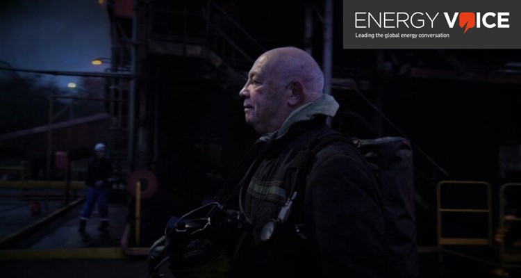 A person in work gear stands in a dark industrial setting. The image is accompanied by the 