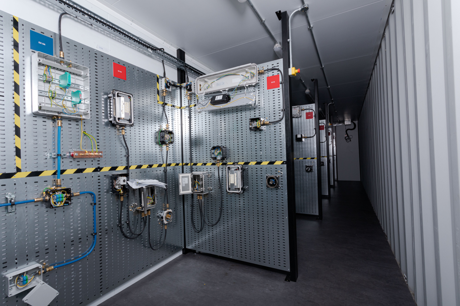 A corridor with industrial control panels and wiring on the walls in a technical facility.