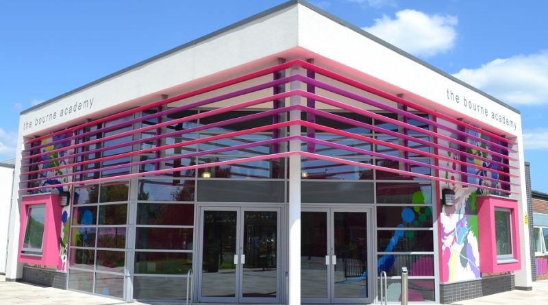 A modern building with pink accents and glass walls under a blue sky. 