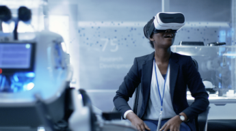 A person in a business suit is seated and wearing a virtual reality headset in a modern, high-tech environment.