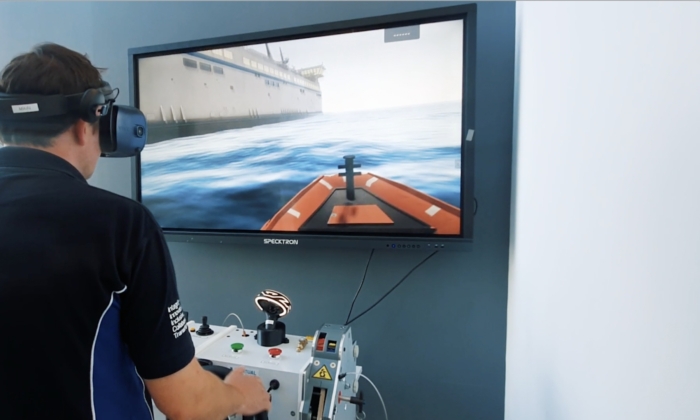 Person wearing a virtual reality headset, using a simulator to control a boat on a screen mounted on the wall.