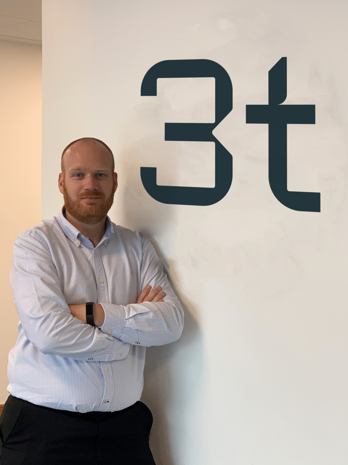 Jamie stands with arms crossed next to a wall displaying the letters 